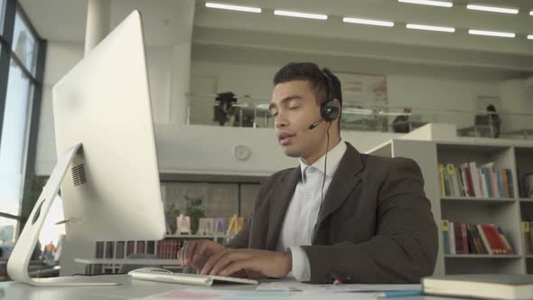 Customer Support Operator with Handsfree Headset Working in the Office in a Business Suit