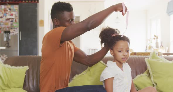 African american father tying his daughter hair