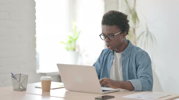 Young African Man Reacting to Loss While Using Laptop