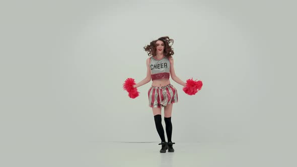 Sportive Girl Dancing a Jubilant Dance with Pompoms in the Studio on a White Background