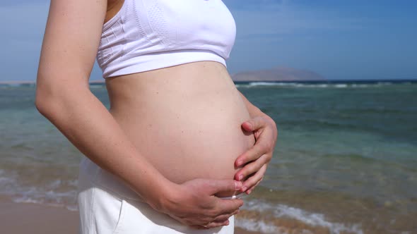 Pregnant Woman Relaxing On The Beach By The Sea