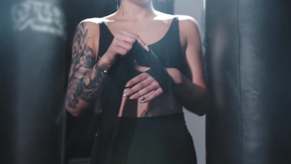 Tattooed Woman Binding Her Hands Before Box Training in Locker Room