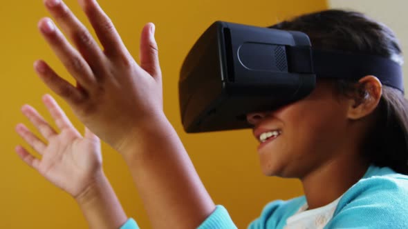 Schoolgirl using virtual reality glasses in classroom at school