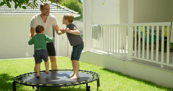 Father playing with kids on trampoline 4k