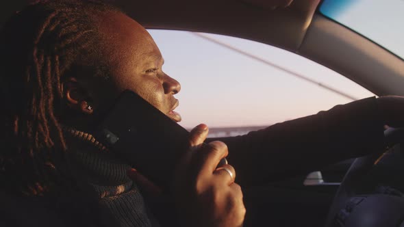 Portrait of Young African American Black Man Speaking on the Phone and Driving