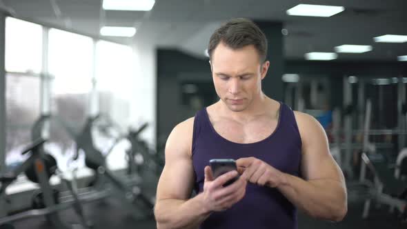 Sportsman Checking Fitness Application in Smartphone, Personal Program Online