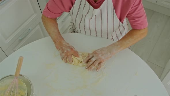 Grandmother is Preparing Dough in the Kitchen