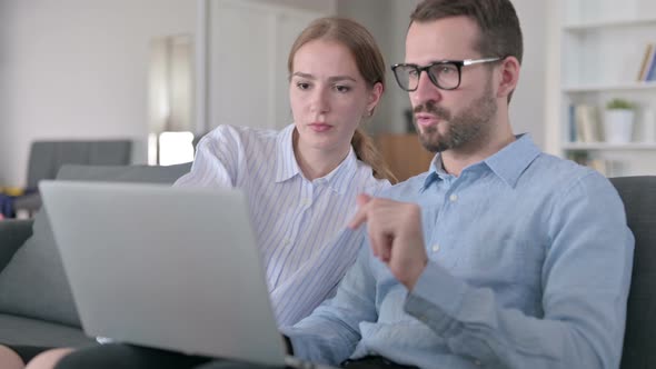 Serious Young Couple Using Laptop at Home 