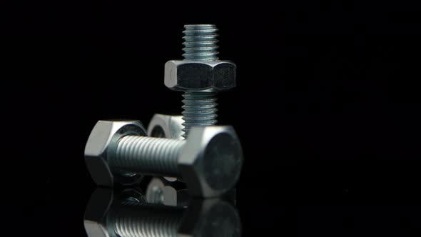 Screws and Bolts on Rotating Plate. Black Studio Background, Closeup