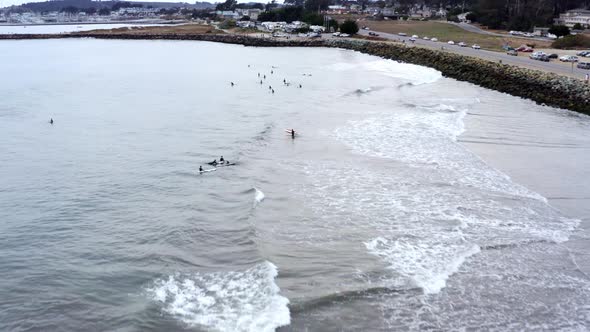 AERIAL: drone, shore, highway 1 and surfers,ing forward view