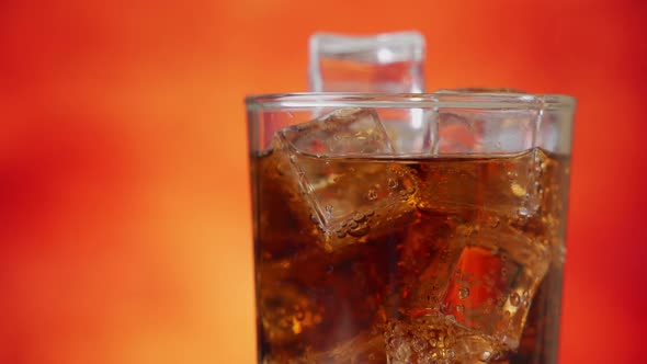 Cola with Ice Cubes Rotate Close-up. Cola with Ice and Bubbles in Glass. Soda Closeup.