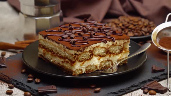 Portion of Traditional Italian Tiramisu dessert and mocha coffee maker on grey concrete background