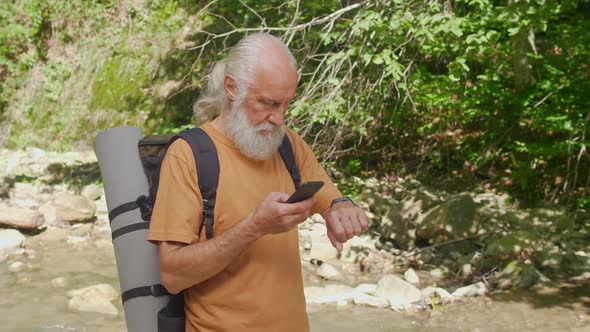 Old Man Uses Bracelet and Mobile Phone While Traveling in the Forest