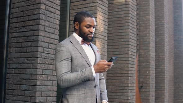 Young Elegant African American Businessman Talking on Phone Near the Office Center