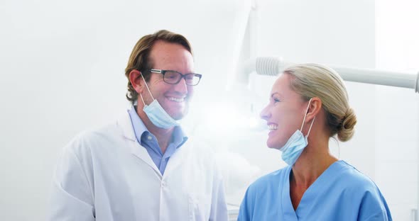 Smiling dentist talking to dental assistant