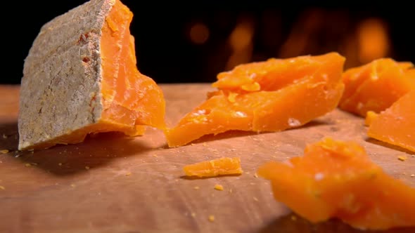 Piece of Mimolett Cheese Falls on a Wooden Board