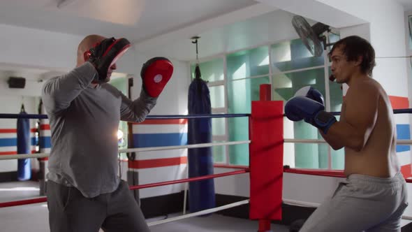 Caucasian man training with coach in boxing ring