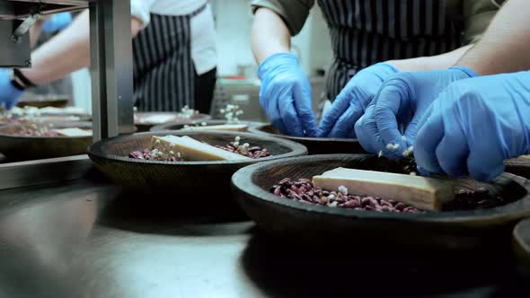 Chef's Hands Preparing a Dish Serving on a Bed of Beans
