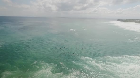 Surfers at Bingin Beach sit on their boards patiently waiting for the perfect wave on a sunny aftern