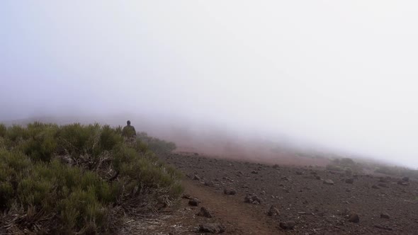 Man Walking Along Stony Ground Under Misty Sky