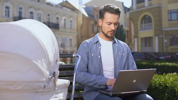 Modern Young Dad Working Laptop and Swinging Baby Pram, Multitasking Lifestyle