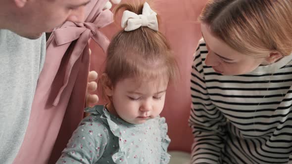 Childhood Young Male and Female Parents Kiss Their Little Daughter with Love and Tenderness During