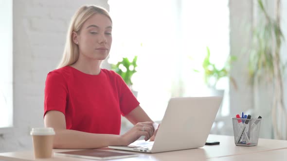 Young Blonde Woman Shaking Head in Rejection While using Laptop in Office