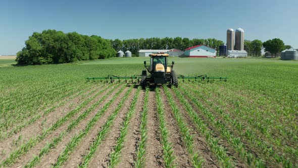 Aerial, farm tractor spraying pesticide onto fresh crops on rural farm field. Series