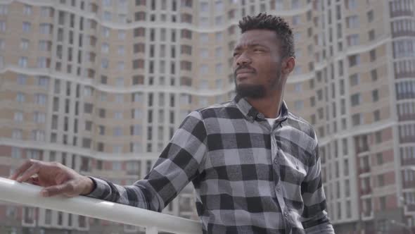 Portrait of Handsome African American Man Standing Against the Background of Urban Architecture. The