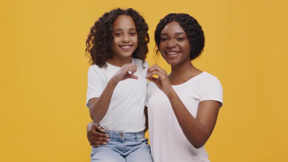 Young Happy African American Mother and Daughter Showing Heart Gesture and Smiling at Camera