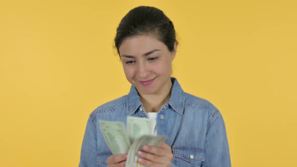 Happy Indian Woman Counting Dollars, Yellow Background 