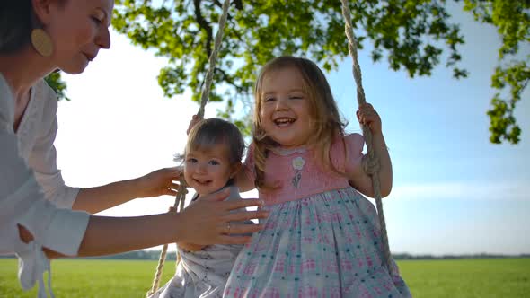 Two Little Sisters, 1 and 3 Years Old, Swinging on a Rope Swing Tied To an Old Oak Tree in a Field