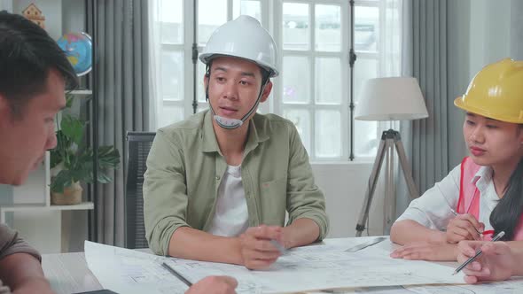 Asian Engineers With Helmets Presenting Work To A Man At The Office