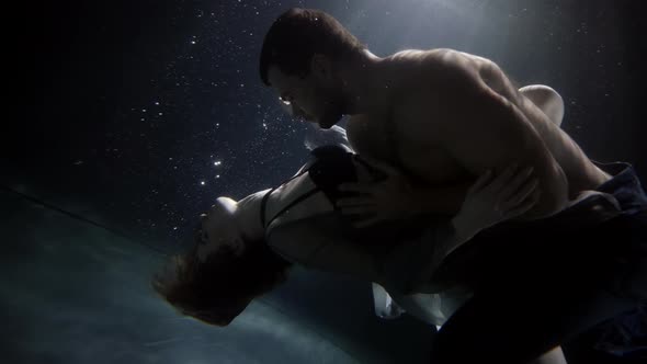 A Man Passionately Touches and Hugs His Girlfriend Underwater Lovers Deep Inside on a Dark