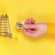 Vertical video Female hand putting golden shiny bitcoin into mini grocery cart - VideoHive Item for Sale