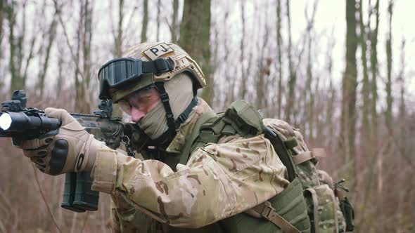 Armed Young Man in a Zone of Armed Conflict in Uniform Targeting with Assault Rifle Walking in