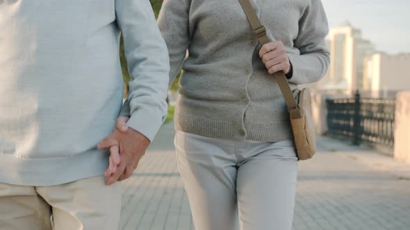 Tiltup Portrait of Senior Man and Woman Walking in City Holding Hands Talking