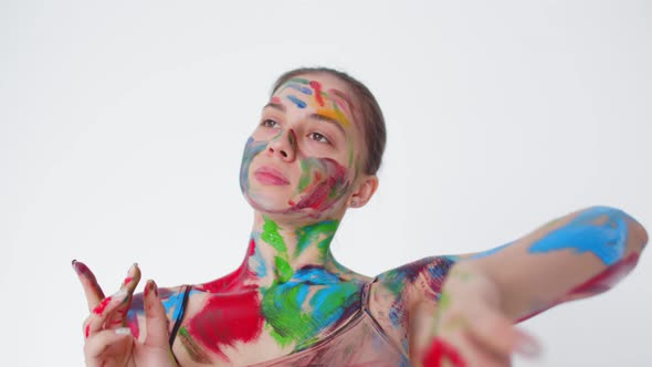 Beautiful dancer in red, green, blue paint dances with her hands, camera movement. Woman is dancing