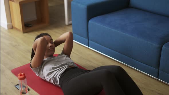 Young African American Female Athlete Working Out in the Living Room Doing Abdominal Exercise