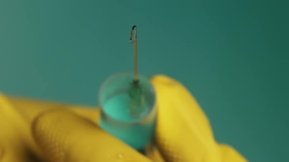 Syringe Needle with Liquid Dripping Drops of Medication in Doctor Hands