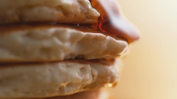 Pouring honey on stack of pancakes. Slow Motion.