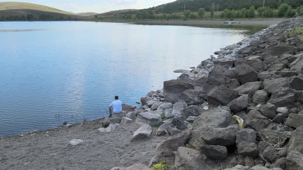 lonely man sitting by the lake