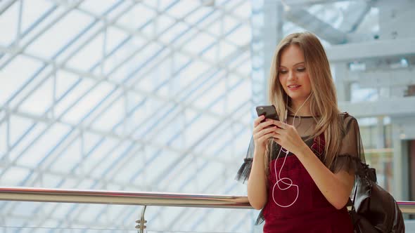 Smiling Female Blogger Listening Favorite Songs in Headphones While Posing for Selfie on Smartphone