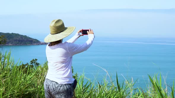 woman wearing hat taking pictures of beach
