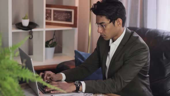 Young, handsome man in a suit working on a laptop at home