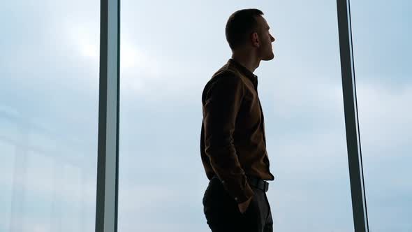 A businessman looks out the window in a contemplative way.