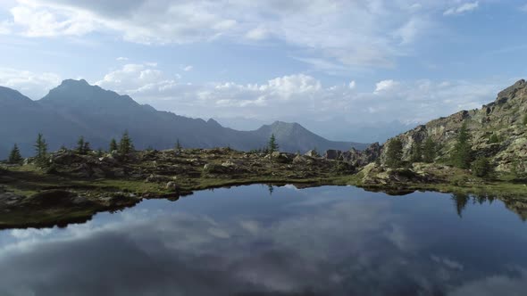 Moving Forward Above Clear Blue Lake and Pine Woods in Sunset Summer Day