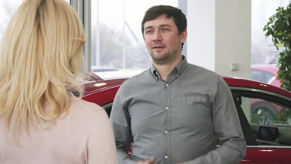 Happy Mature Man Handing Car Keys To a New Auto To His Loving Wife