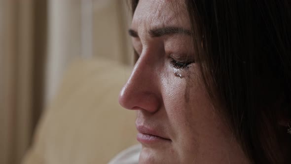 Closeup of a Crying Young Woman with Blurry Mascara Dripping Down Her Cheeks