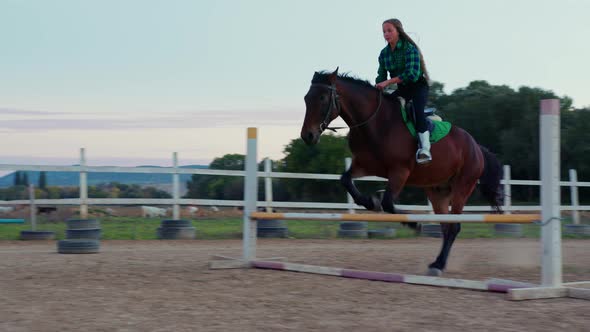 A Teenage Girl Astride the Horse Jumping the Hurdles